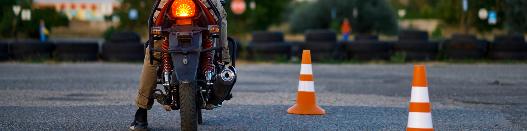 A new motorcycle rider practices low-speed control and balance in a training area marked with cones, representing confidence-building skills taught in a new rider program.